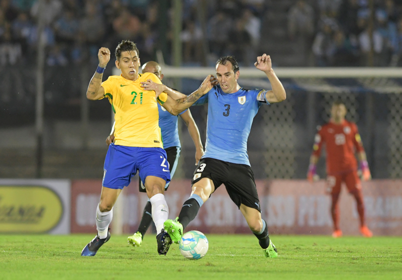 MONTEVIDEO, URUGUAY - MARCH 23: Roberto Firmino of Brazil and Diego Godin of Uruguay fight for the ball during a match between Uruguay and Brazil as part of FIFA 2018 World Cup Qualifiers at Centenario Stadium on March 23, 2017 in Montevideo, Uruguay. (Photo by Sandro Pereyra/LatinContent via Getty Images)