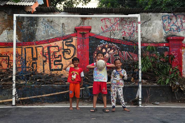 Kids pose for a photo at Lapangan Delima football pitch in Jakarta, Indonesia