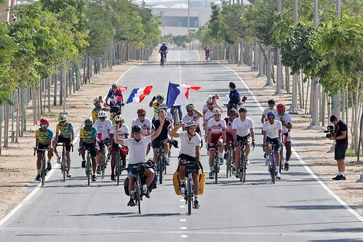 French soccer fans Gabriel Martin (center L) and Mehdi Balamissa (center R), who cycled from Paris for the Qatar 2022 World Cup football tournament, arrive in Doha