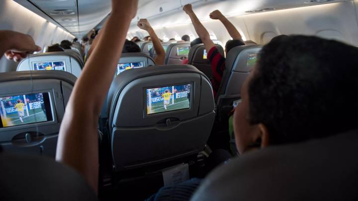 TOPSHOT - Brazilian football fans reacts to Neymar scoring against Cameroon as they watch the match live on TV in flight above the Amazonian jungle on June 23, 2014. The Azul flight from Manaus bound for Sao Paulo offered live streaming of the Brazil and Cameroon FIFA 2014 World Cup football match and the plane erupted in cheers when Brazil took an early lead. AFP PHOTO / ODD ANDERSEN (Photo by Odd ANDERSEN / AFP) (Photo by ODD ANDERSEN/AFP via Getty Images)