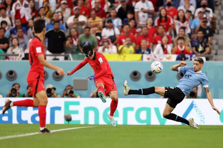 Heungmin Son of Korea Republic crosses the ball against Federico Valverde of Uruguay