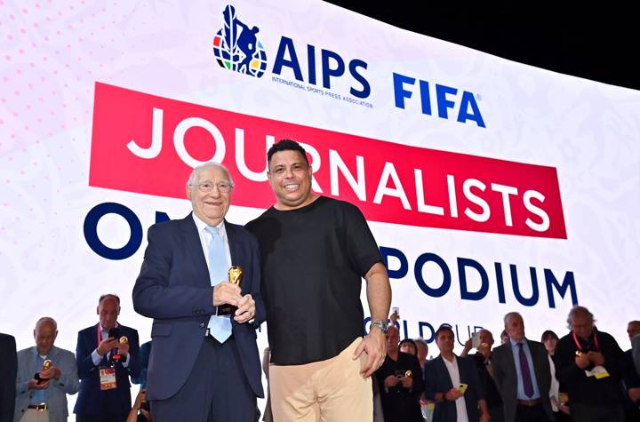 Enrique Macaya Márquez is presented with a world cup replica trophy by Ronaldo