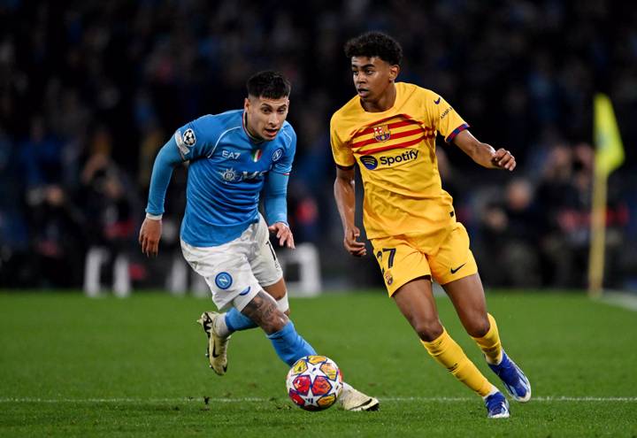 Lamine Yamal of FC Barcelona runs with the ball whilst under pressure from Mathias Olivera of SSC Napoli during the UEFA Champions League 2023/24 round of 16 first leg match