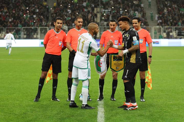 Captains Yacine Nasr-Eddine Brahimi of Algeria and Ronwen Williams of South Africa shake hands and exchange match pennants