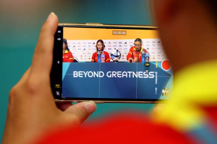 A mobile phone is seen filming as Pham Hai Yen and Mai Duc Chung, Head Coach of Vietnam, speak to the media 