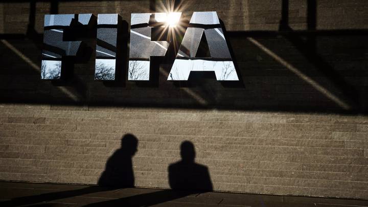 A picture taken on March 18, 2016 shows men casting their shadow next to a FIFA logo at the FIFA headquarters in Zurich. / AFP / MICHAEL BUHOLZER (Photo credit should read MICHAEL BUHOLZER/AFP via Getty Images)